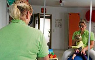 Lydia Huber zeigt am Beispiel ihrer zweijährigen Tochter Karla, wie das Bobath- Konzept die Kleine zum Stehen bringt. Auch sie ist entwicklungsverzögert. Foto: Marcus Pfeiffer